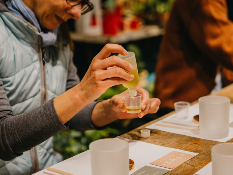 A woman wearing glasses decants essential oils into a small glass container